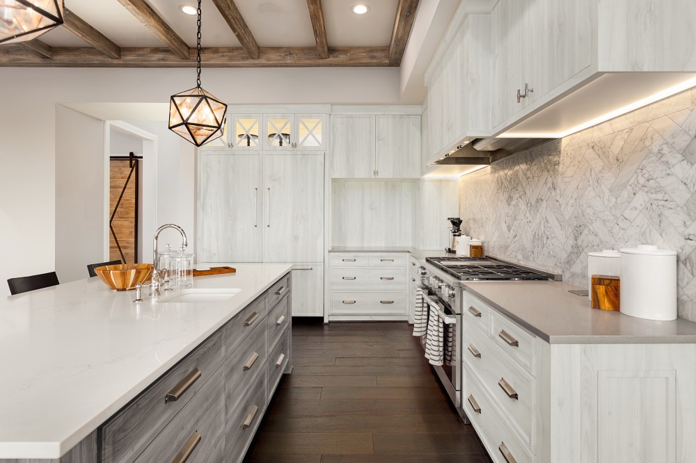 beautiful kitchen in new luxury home with island, pendant lights, and hardwood floors.