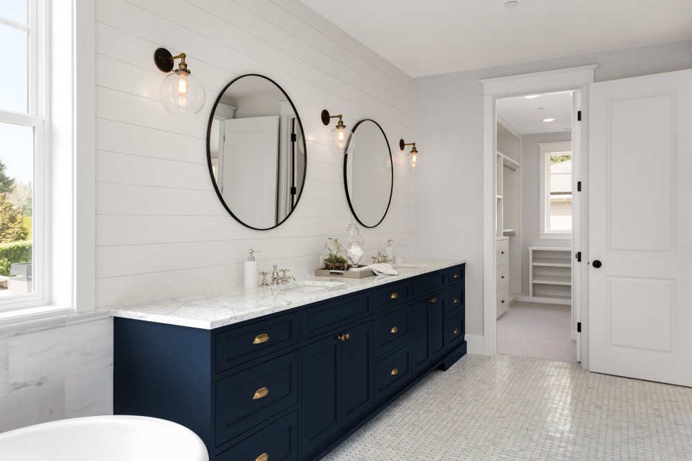 Bathroom in New Luxury Home with Two Sinks and Dark Blue Cabinets. Shows Walk-In Closet